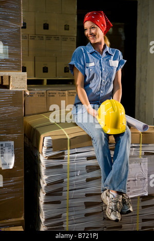 Arbeitnehmerin sitzen auf Karton Kisten im Lagerhaus Stockfoto