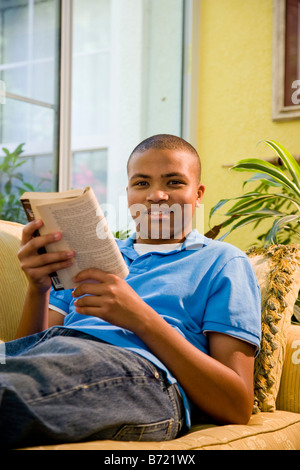 African American Teenager Buch auf couch Stockfoto