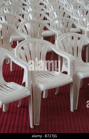 Große Anzahl von weißer Farbe Stühle auf roten Teppich für wichtige öffentliche Funktion angeordnet oder treffen sich in einen riesigen Konferenzsaal Stockfoto