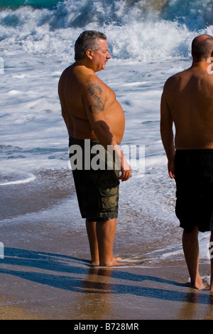 Palm Beach Shores, Florida, stattlicher Mann mittleren Alters mit Tattoo auf dem Sand in der Sonne am Meer Ufer paddeln Stockfoto