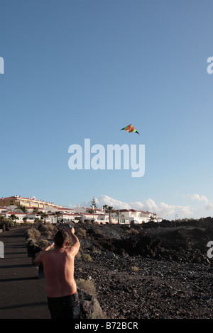 Eine junge fliegt einen Drachen in einem klaren blauen Himmel an der Küste in Playa San Juan-Teneriffa-Kanarische Inseln-Spanien Stockfoto