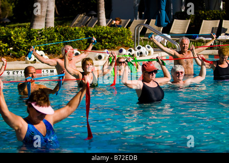 Palm Beach Shores, lächelnd mittleren Reife im Alter von großen Männern & Frauen im Schwimmbad machen Aqua Aerobic mit elastischen Stretch-Streifen Stockfoto