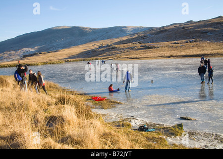 Snowdonia Gwynedd North Wales Januar Menschen gehen und spielen auf einem zugefrorenen See nach Nächten der niedrigen Temperaturen Stockfoto