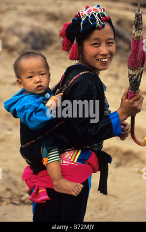 Ein Hmong Mädchen trägt ein Baby auf ihrem Rücken auf dem Lande in der Nähe von Luang Prabang, Nordlaos Stockfoto