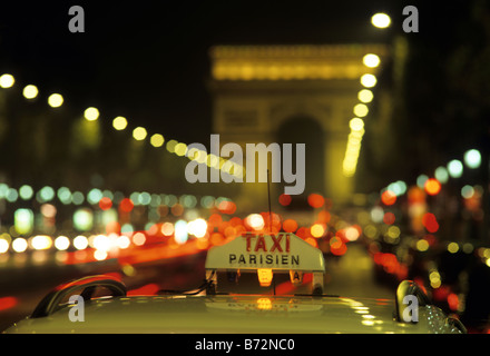 Parisien Taxi auf Champs-Élysées in der Nacht mit Arc de Triomphe im Hintergrund Stockfoto