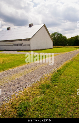 Eine ländliche Schotterstraße und Scheune auf einem sonnigen Tag befindet sich in Tennessee, USA. Stockfoto