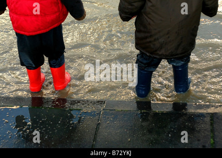 Kinder Gummistiefel tragen und spielen in Pfützen Stockfoto