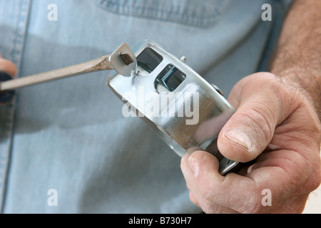 Elektriker mit Hilfe eines Schraubendrehers die Knock Outs Registerkarten aus einem elektrischen Feld zu entfernen, die Arbeit an Code ausgeführt wird Stockfoto