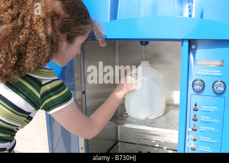 Eine teenie Girl füllen eine Flasche Wasser am Automaten in der Vorbereitung für einen Hurrikan könnte auch verwendet werden, für das recycling Stockfoto