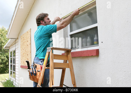 Ein Mann messen Windows für Hurrikan Fensterläden oder Sperrholz Stockfoto