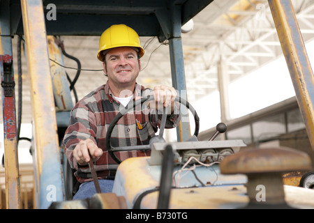 Ein hübscher Bauarbeiter fahren einen Bulldozer auf einer Baustelle Stockfoto