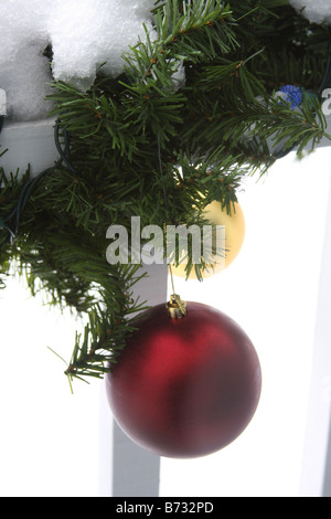 Ornamente aus eine Weihnachtsgirlande hängen eine Veranda Geländer mit Schnee Stockfoto