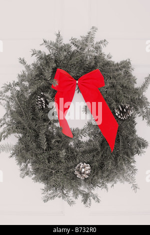 Ein Weihnachtskranz an der weißen Eingangstür von einer Heimat roten Schleife hängen Stockfoto