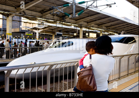 Mutter und Kind beobachten einen 300 und 700 Serie Shinkansen-Zug am Bahnhof Tokio. Stockfoto