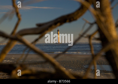 Sonnenaufgang über dem Folly Beach anzeigen Morris Leuchtturm durch Treibholz in der Nähe von Charleston SC Morris Lighthouse stammt aus dem Jahre 1767 Stockfoto
