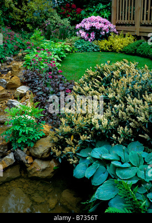 Steingarten und Wassergarten mit gemischten Beet und Rasen Stockfoto