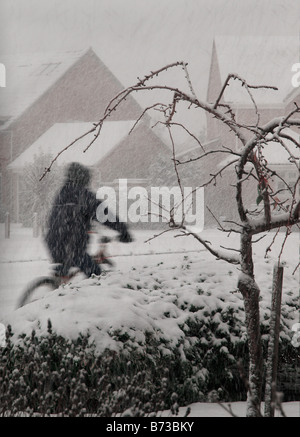 Lebensstil-Bild, ein Radfahrer durch heftige Schneefälle in Norfolk Wohnsiedlung, weißen Winter Tag UK Stockfoto