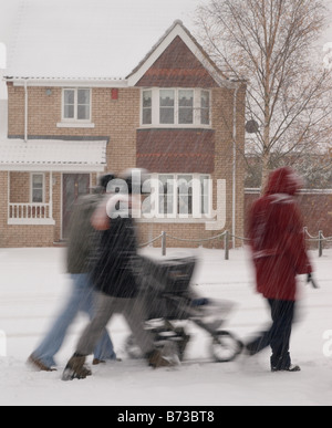 Lebensstil Bild Gruppe von Menschen zu Fuß durch Schneefall in Wohnsiedlung Norfolk Uk Stockfoto