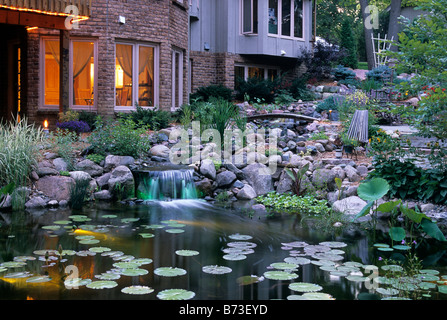 WASSERFÄLLE UND KLEINE BOND VON UNTERWASSER FASEROPTISCHE BELEUCHTUNG IN MINNESOTA HAUSGARTEN DÄMMERUNG BELEUCHTET. Stockfoto