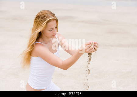 Frau sieben Sand durch ihre Hände Stockfoto