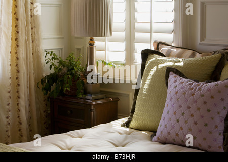 Lila und grün dekorative Kissen auf dem Bett in der Nähe von Fenster Stockfoto