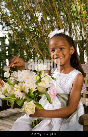 Glücklich afroamerikanische Blume Mädchen sitzen auf Gartenbank mit Blumenstrauß Stockfoto