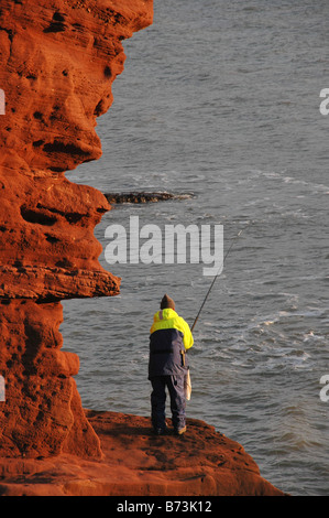 Ein Angler Fischen abseits der Felsen von den Seaton Klippen von Arbroath, Angus. Schottland. Stockfoto