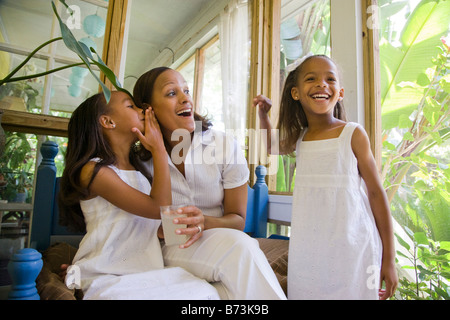 Glückliche afrikanisch-amerikanischen Mutter und Töchter im Wintergarten zu flüstern Stockfoto