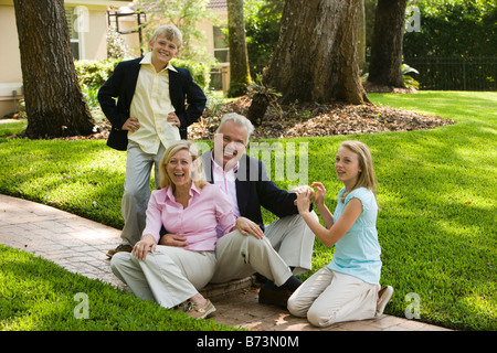 Vierköpfige Familie Zusammensitzen im Freien in Sonntag Kleidung gekleidet Stockfoto