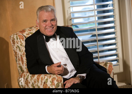 Porträt von mittlerem Alter Mann mit Smoking im Stuhl sitzen Stockfoto