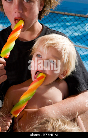 Nahaufnahme der Brüder lecken Eis am Stiel im Wasserpark Stockfoto