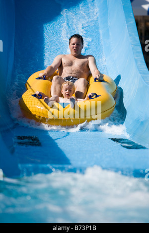 Vater und Sohn Wasser Rutschen rutschen zusammen auf Innertube im Wasserpark Stockfoto