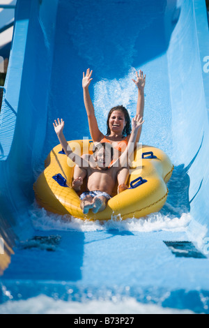 Mutter und Sohn Wasser Rutschen rutschen zusammen auf Innertube im Wasserpark Stockfoto