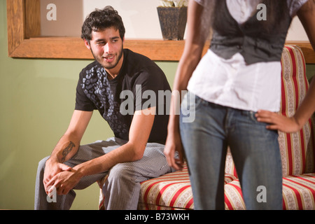 Junger Mann sitzt auf osmanischen mit Mittelteil der jungen Frau im Blick Stockfoto