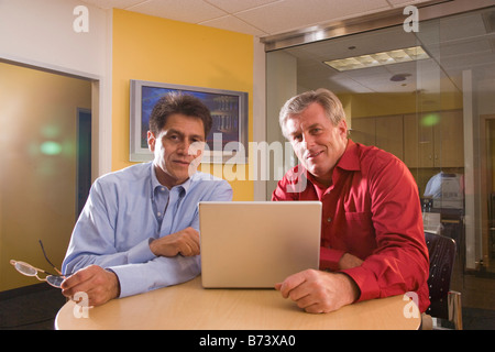 Zwei multi-ethnischen mittleren Alters Geschäftsleute mit Laptop im Büro Stockfoto
