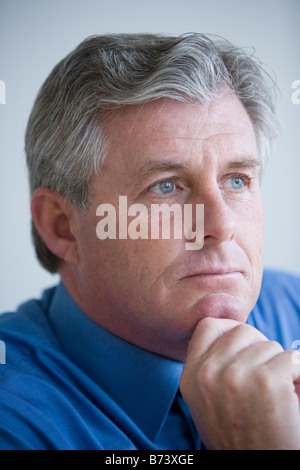 Gesicht des mittleren Alters Geschäftsmann beobachten mit Hand am Kinn Stockfoto