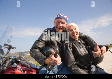 Glücklich senior Biker paar sitzend gelehnt Motorrad auf Feldweg Stockfoto