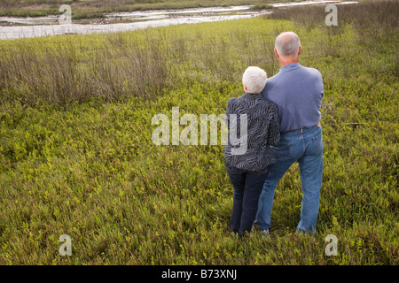 Älteres paar stehen in Grünland mit Arm in Arm, Rückansicht Stockfoto
