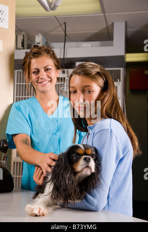 Junges Mädchen mit Hund in der Tierklinik neben Tierarzthelferin Stockfoto