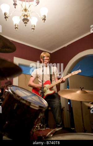 Junger Mann im Haus mit Band Gitarre spielen Stockfoto