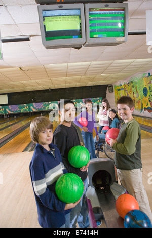 Multi-ethnischen Freundeskreis mit Mädchen im Rollstuhl auf Bowling-Bahn Stockfoto