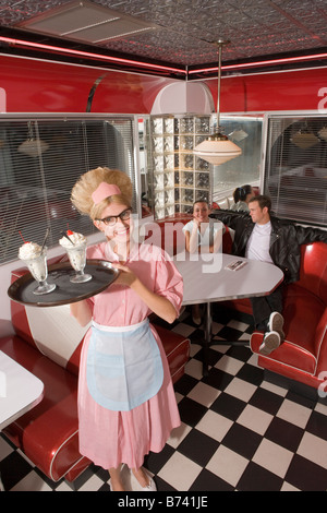 Glücklich Kellnerin im Stil der 1950er einheitliche Eisbecher im Diner serviert Stockfoto