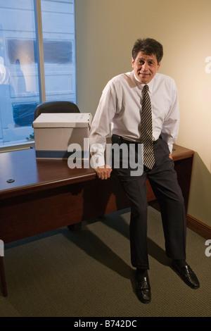 Porträt von mittlerem Alter Geschäftsmann stützte sich auf Schreibtisch in leeren Büro Stockfoto