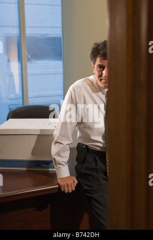 Porträt von mittlerem Alter Geschäftsmann stützte sich auf den Schreibtisch im Büro Stockfoto