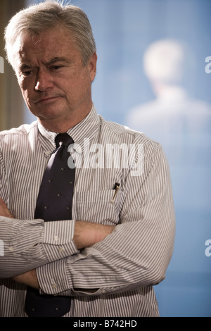 Kontemplative im mittleren Alter Geschäftsmann, stehend im Büro Stockfoto