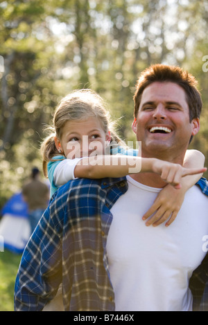 Vater mit Mädchen Huckepack Fahrt im park Stockfoto