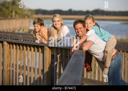 Porträt junge glückliche Familie entspannend auf Geländer von Steg Stockfoto