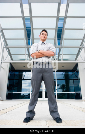 Geschäftsmann, stehend mit Armen gefaltet außen Bürogebäude Stockfoto