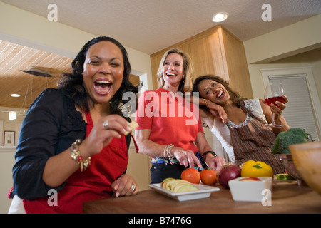 Glückliche multiethnischen Frauen halten Obst und Rotwein in modernen Küche Stockfoto