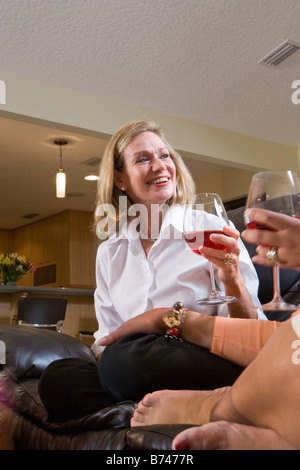 Glückliche Frau Weintrinken im Wohnzimmer Gespräch anhören Stockfoto